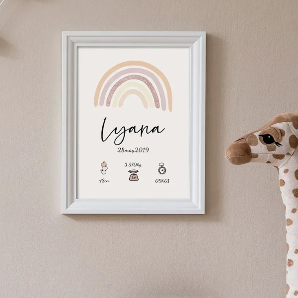 poster personnalisé naissance avec arc-en-ciel dans un cadre blanc accroché à un mur beige à côté d'une girafe en peluche