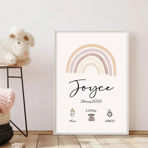 affiche de naissance personnalisée avec arc-en-ciel pastel et cadre bois clair posée sur un tabouret dans une chambre bébé
