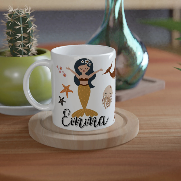 Mug personnalisé tout blanc avec prénom, illustration de sirènes et éléments marins, parfait pour un cadeau enfant original.