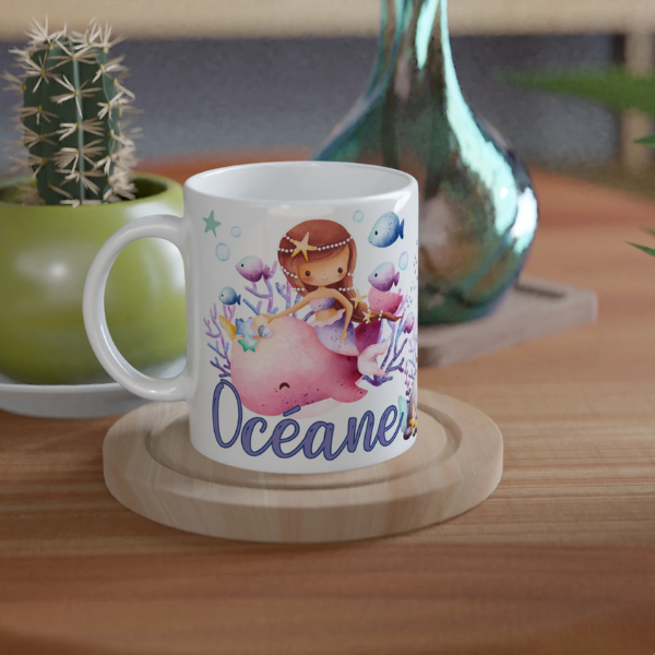 Mug personnalisé tout blanc avec illustration de sirènes et animaux marins, comme des méduses et hippocampes, idéal pour un cadeau enfant.