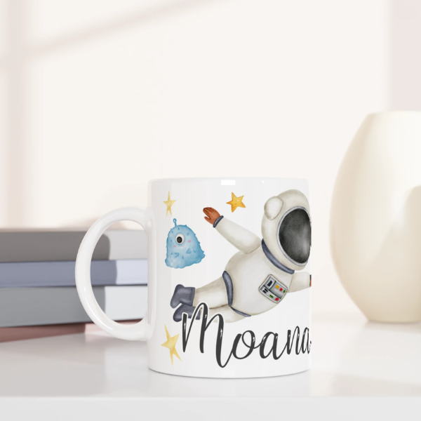Mug personnalisé tout blanc avec astronaute flottant dans l’espace et extraterrestres, parfait pour un cadeau enfant original.