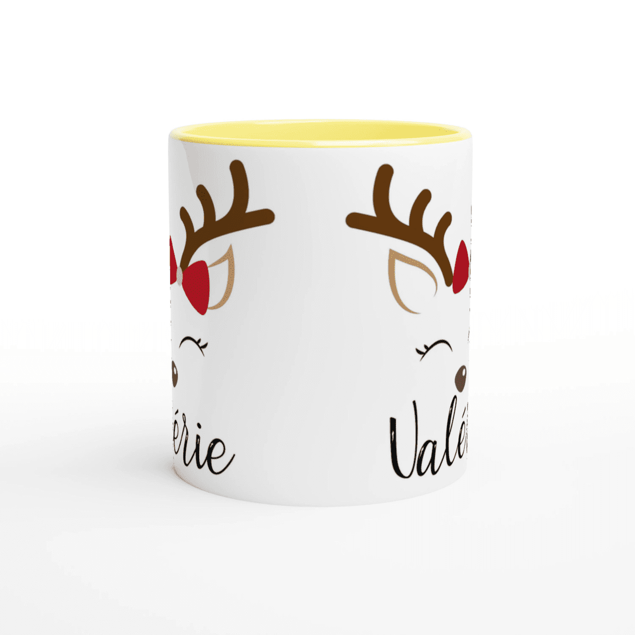 Mug blanc de Noël avec motif renne aux yeux fermés et nœud rouge, anse jaune et intérieur jaune.