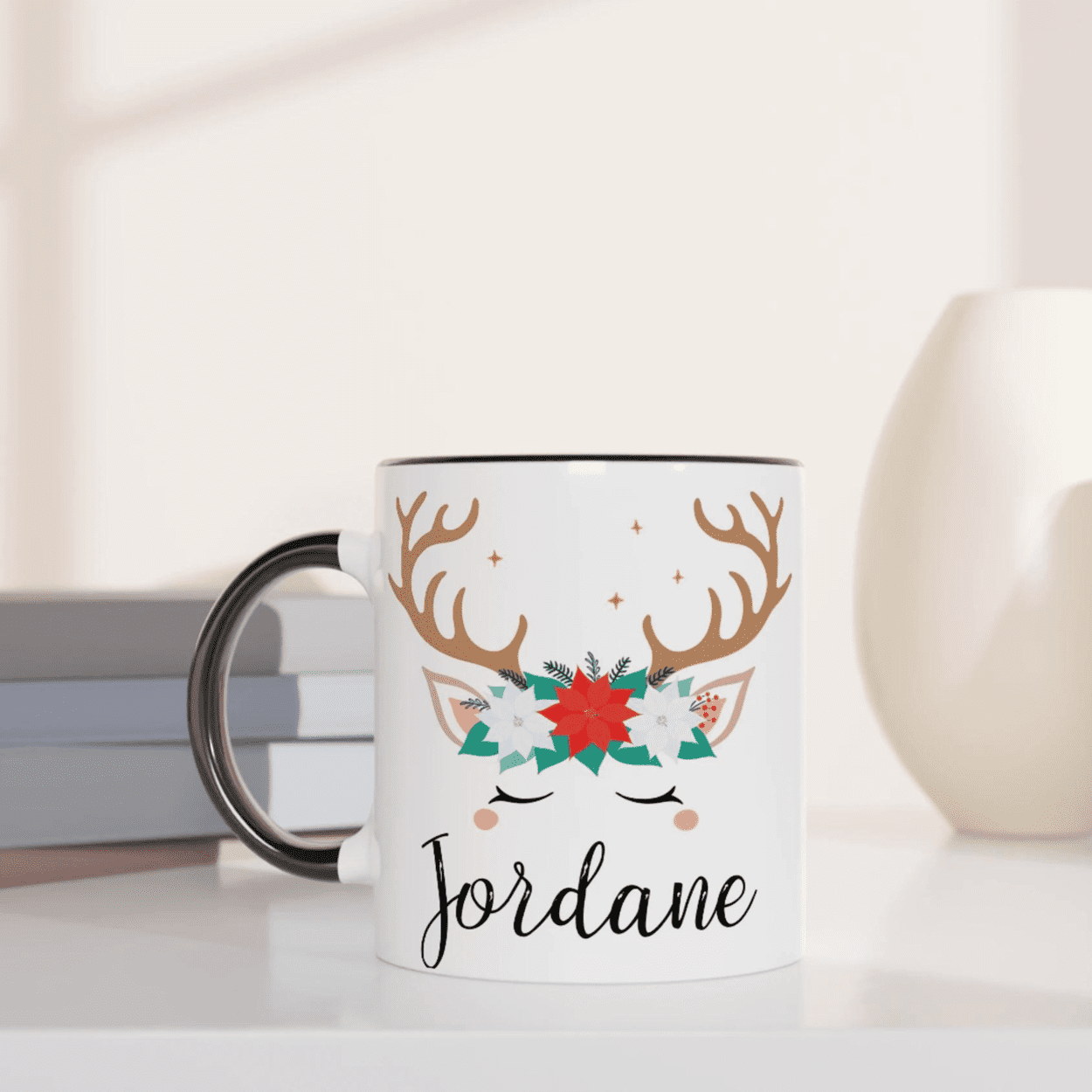 Mug blanc décoré d’un renne avec bois marron et couronne florale rouge et verte, anse noire et intérieur noir.