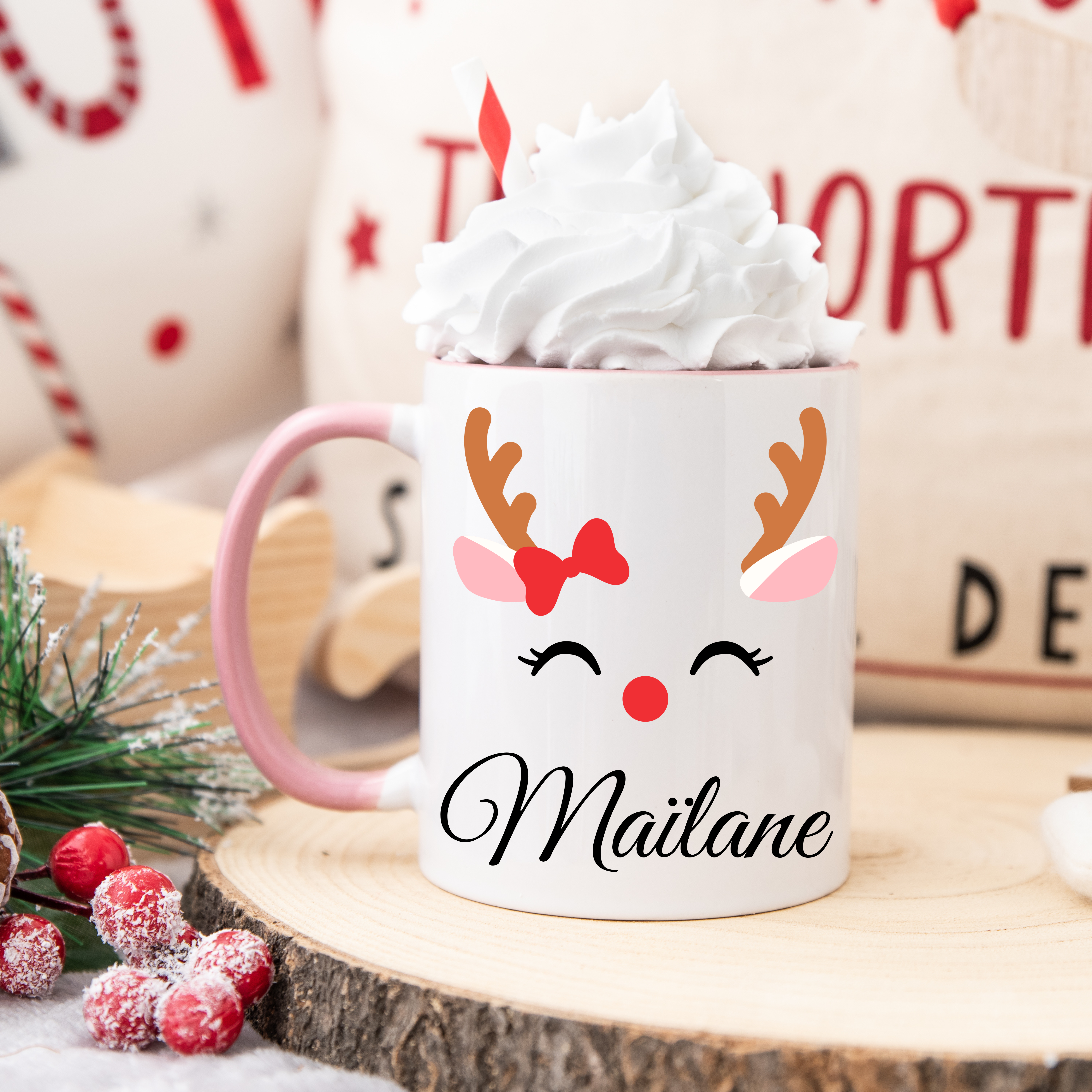 Mug de Noël décoré d’un renne festif avec nœud rouge et bois stylisés, anse rose et intérieur rose.