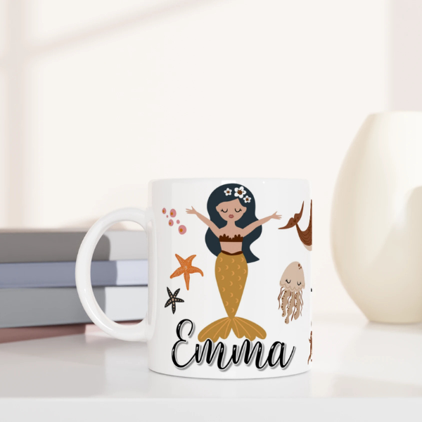 Mug personnalisé tout blanc avec prénom, illustration de sirènes et éléments marins, parfait pour un cadeau enfant original.