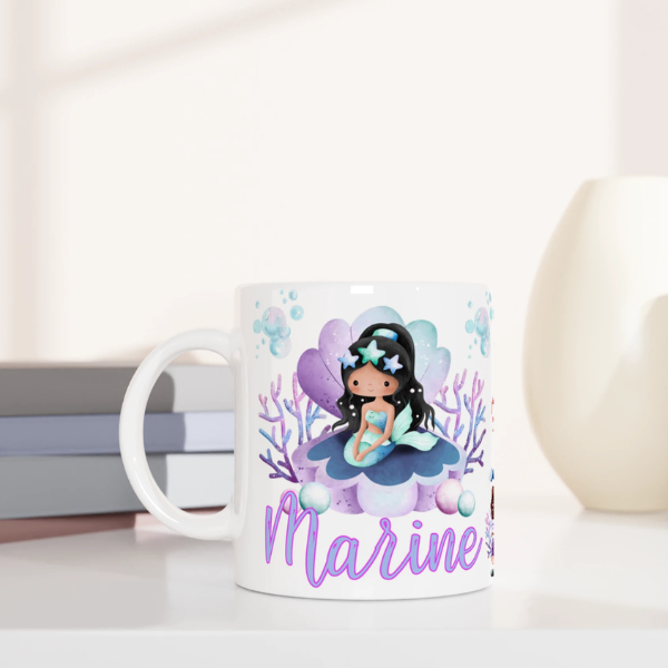 Mug personnalisé tout blanc avec illustration de sirène assise sur un coquillage magique, coraux et décor marin, idéal comme cadeau enfant.