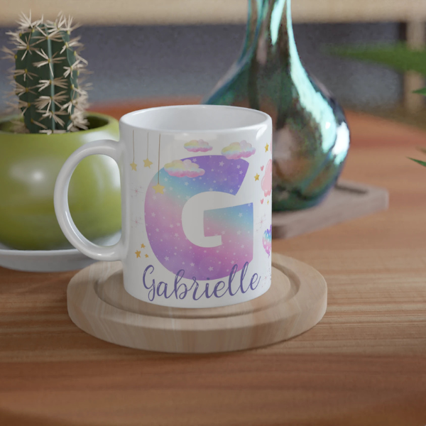 Mug personnalisé tout blanc avec licorne ailée et lettre initiale étoilée, idéal pour un cadeau magique et féerique.