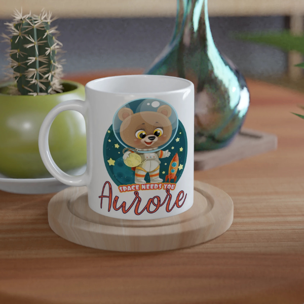 Mug personnalisé tout blanc avec ourson astronaute tenant une planète, parfait pour un cadeau enfant original et ludique.