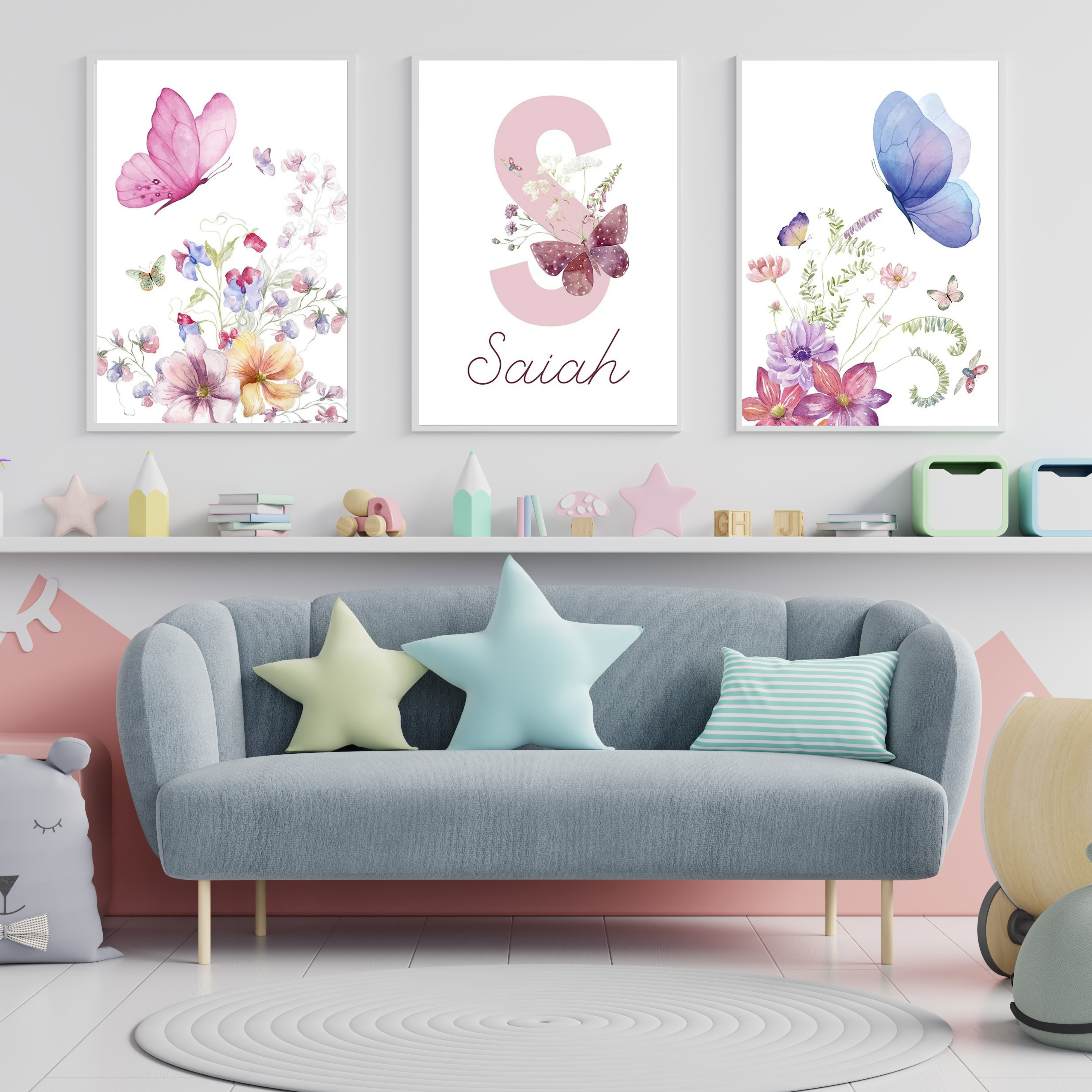 Triptyque d’affiches murales avec papillons et fleurs à l’aquarelle dans des tons pastel, décorant un salon ou une chambre d’enfant avec canapé gris, coussins étoile et décoration douce.