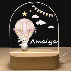 Veilleuse personnalisable rose avec prénom - Design lapin et ballons. Idéale pour une chambre de bébé fille, cette veilleuse LED en bois et acrylique diffuse une lumière douce et apaisante.