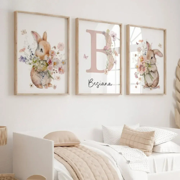 Affiches murales représentant des lapins à l’aquarelle et une lettre florale décorative, accrochées au mur au-dessus d’un lit dans une chambre d’enfant aux tons neutres et apaisants.