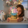 Lampe veilleuse licorne LED personnalisée tenue par un enfant dans une chambre cosy