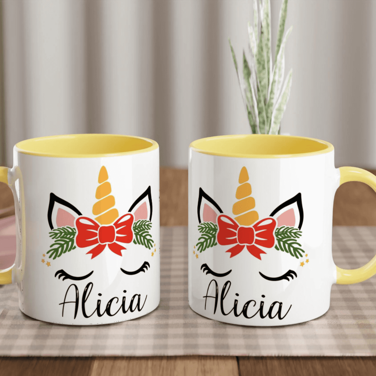 Mug blanc motif licorne de Noël avec feuillage vert et nœud rouge, anse jaune et intérieur jaune.