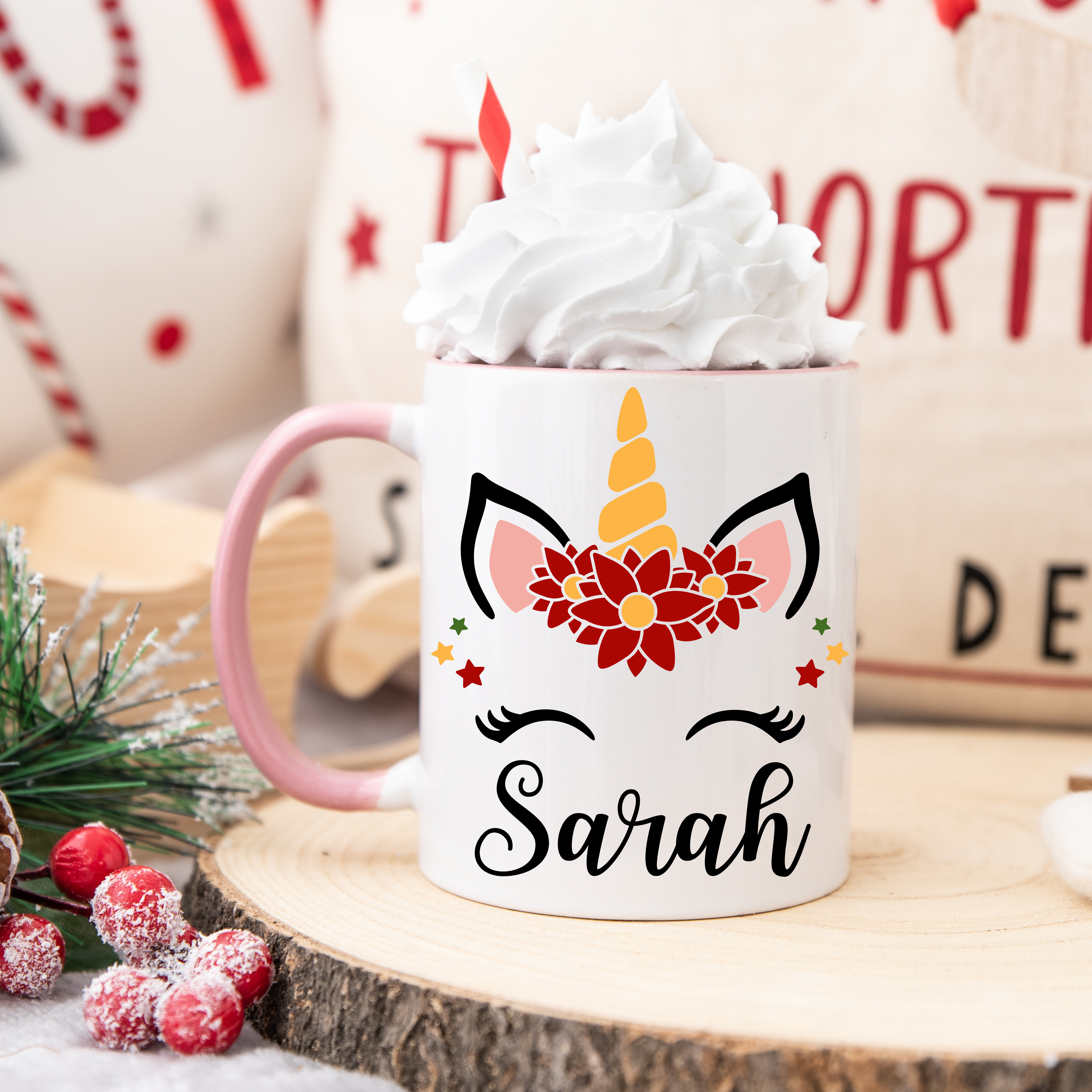 Mug blanc décor licorne de Noël avec couronne de fleurs rouges, étoiles festives et corne dorée, anse rose et intérieur rose.