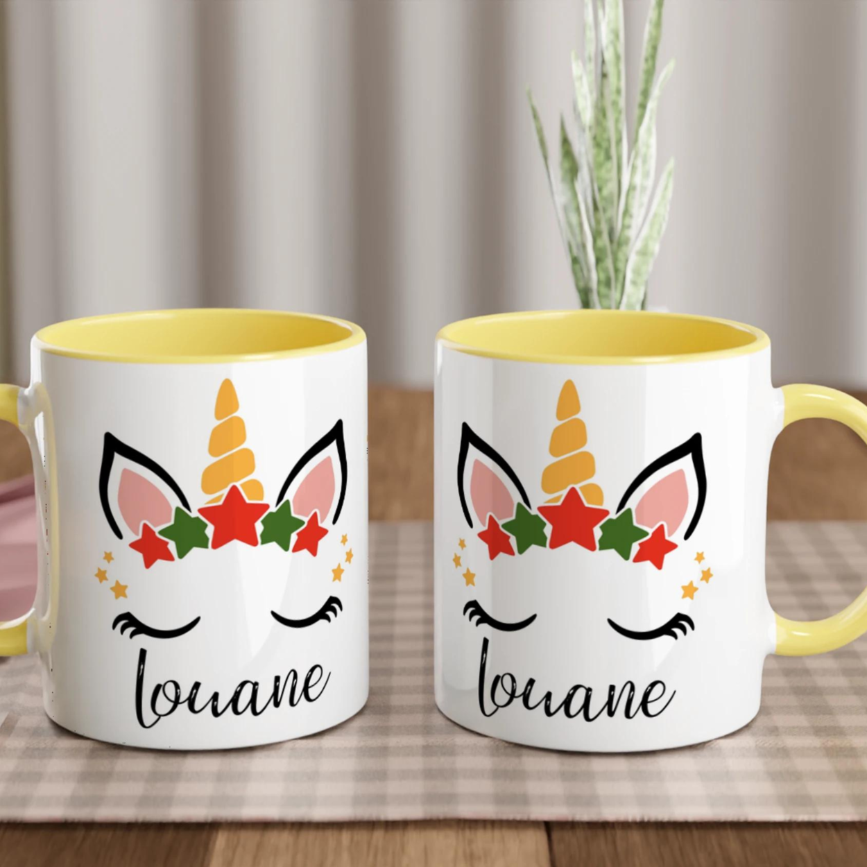 Mug licorne de Noël avec corne dorée et couronne d’étoiles rouges et vertes, anse jaune et intérieur jaune.
