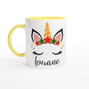 Mug licorne de Noël avec corne dorée et couronne d’étoiles rouges et vertes, anse jaune et intérieur jaune.