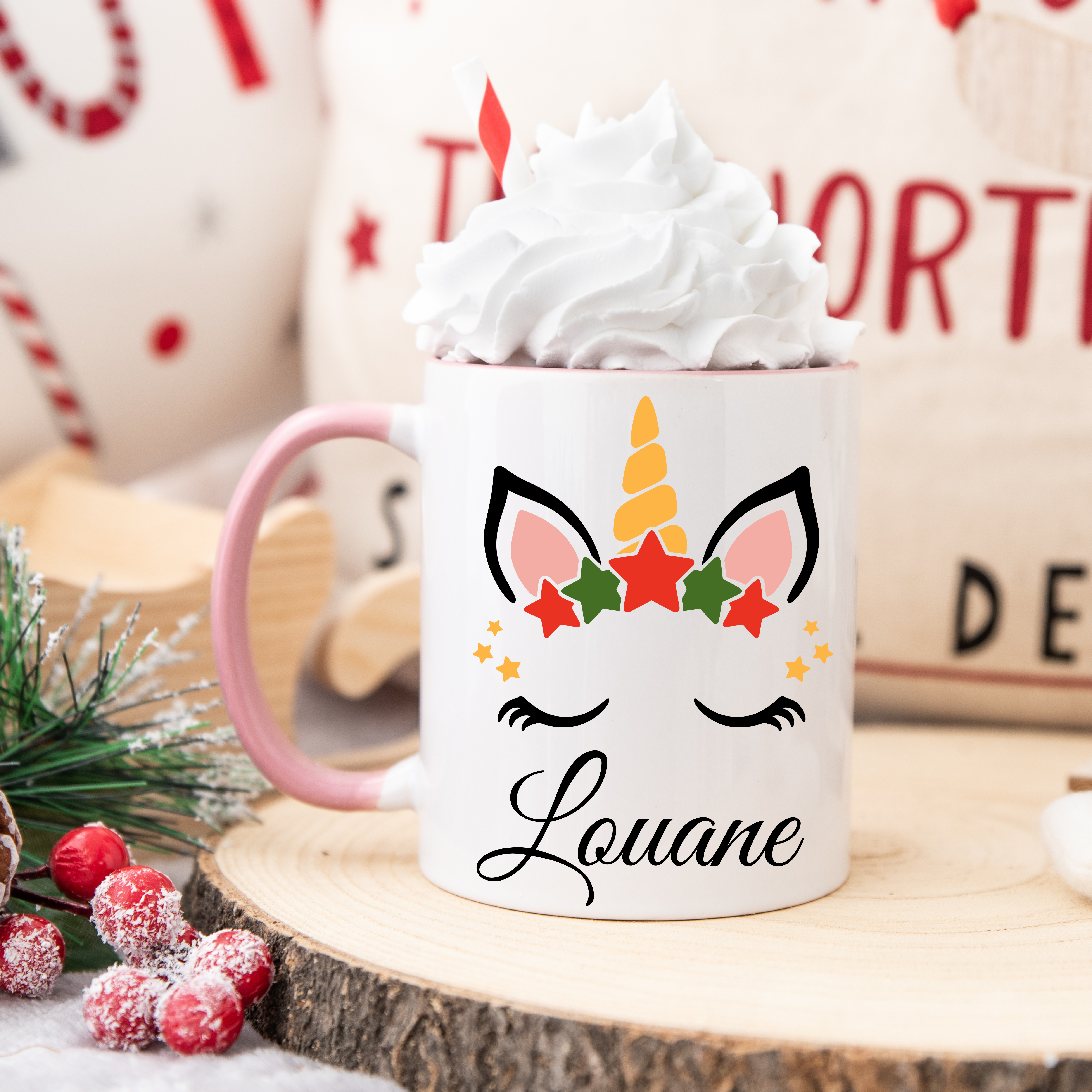 Mug licorne de Noël avec corne dorée et couronne d’étoiles rouges et vertes, anse rose et intérieur rose.