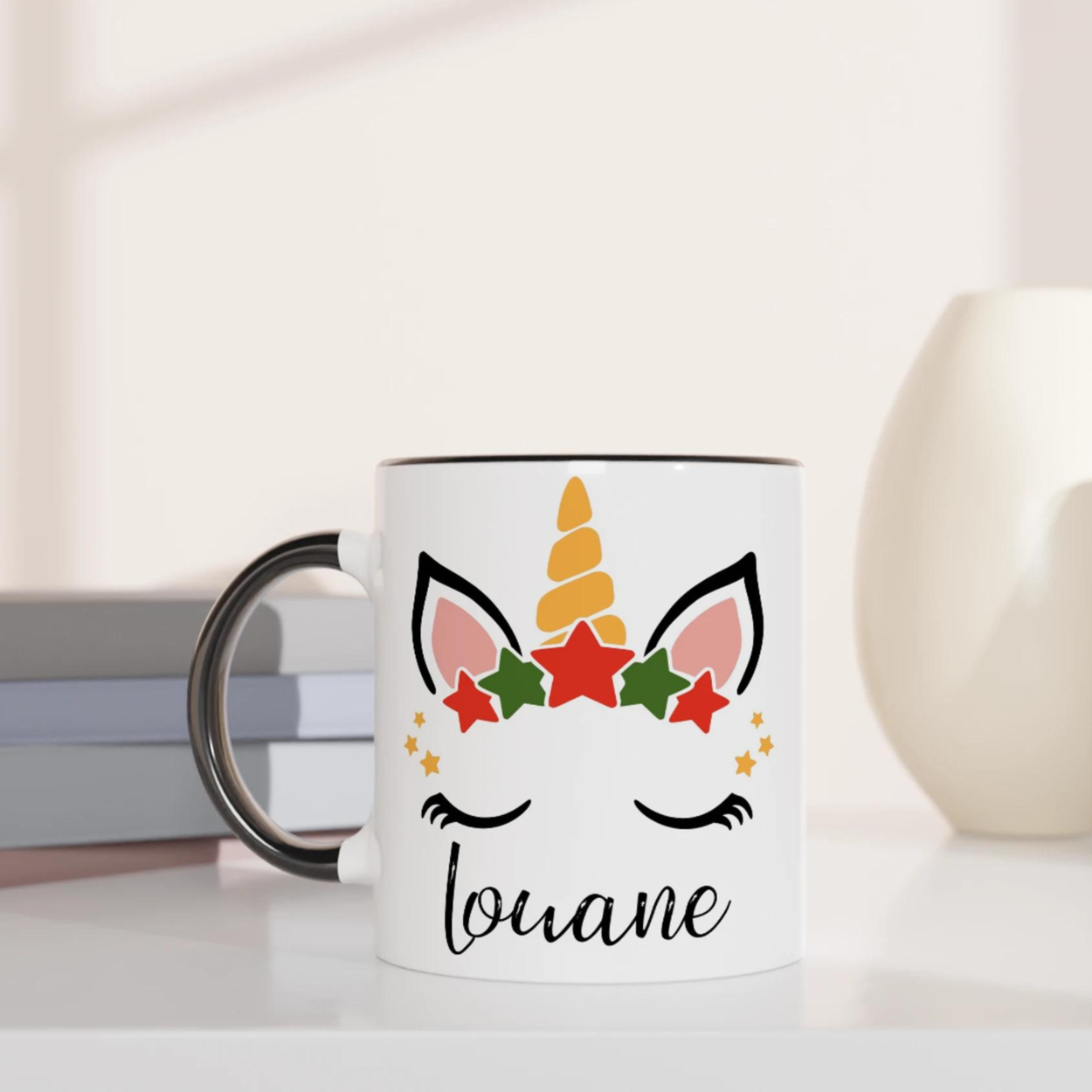 Mug licorne de Noël avec corne dorée et couronne d’étoiles rouges et vertes, anse noire et intérieur noir.
