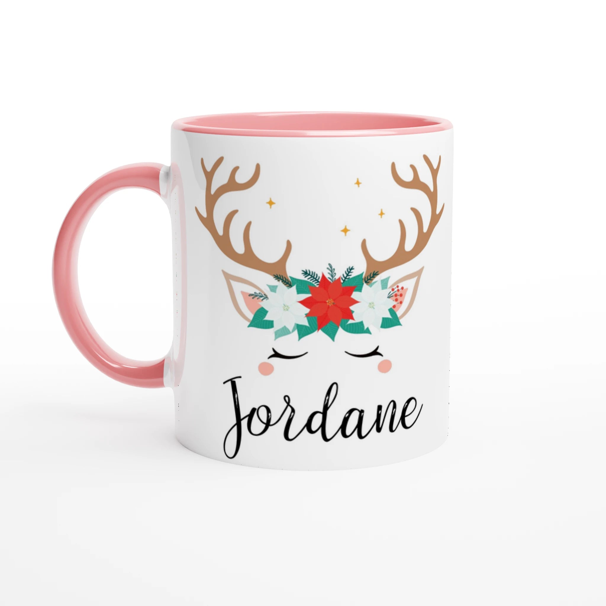 Mug de Noël avec motif renne et couronne florale, anse rose et intérieur rose, posé sur une table avec chantilly et décoration festive.