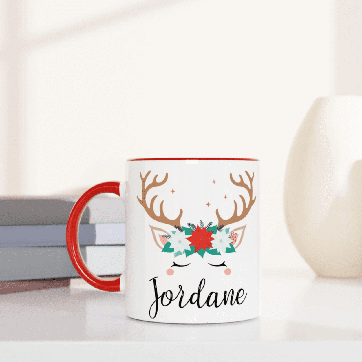 Mug blanc avec illustration de renne et couronne de fleurs de Noël, anse rouge vif et intérieur rouge.