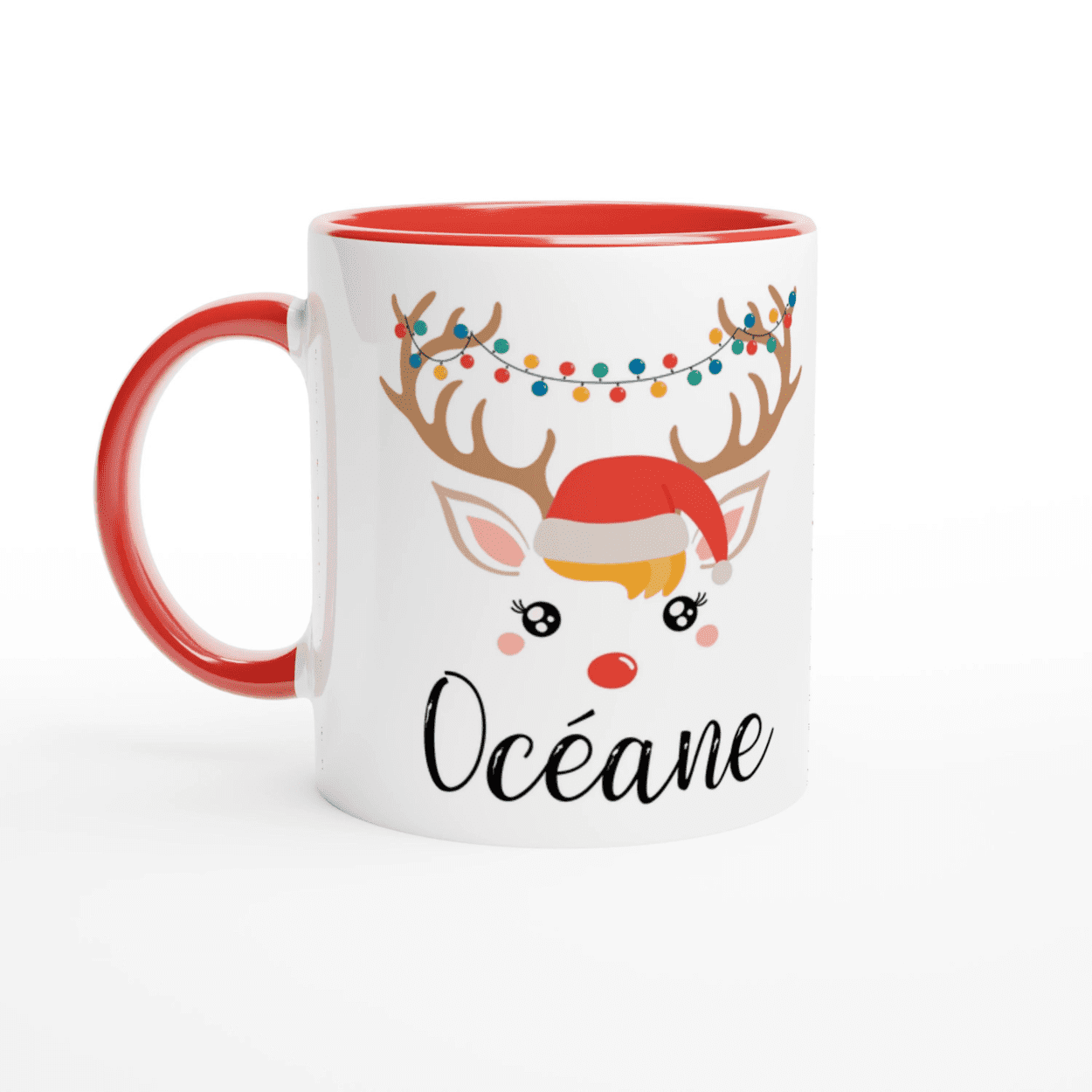 Mug de Noël décoré d’un renne avec bonnet rouge et guirlande lumineuse colorée, anse rouge et intérieur rouge.