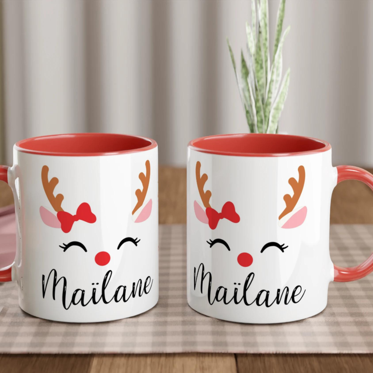 Mug de Noël illustré d’un renne avec nœud rouge et nez rouge, anse rouge et intérieur rouge.