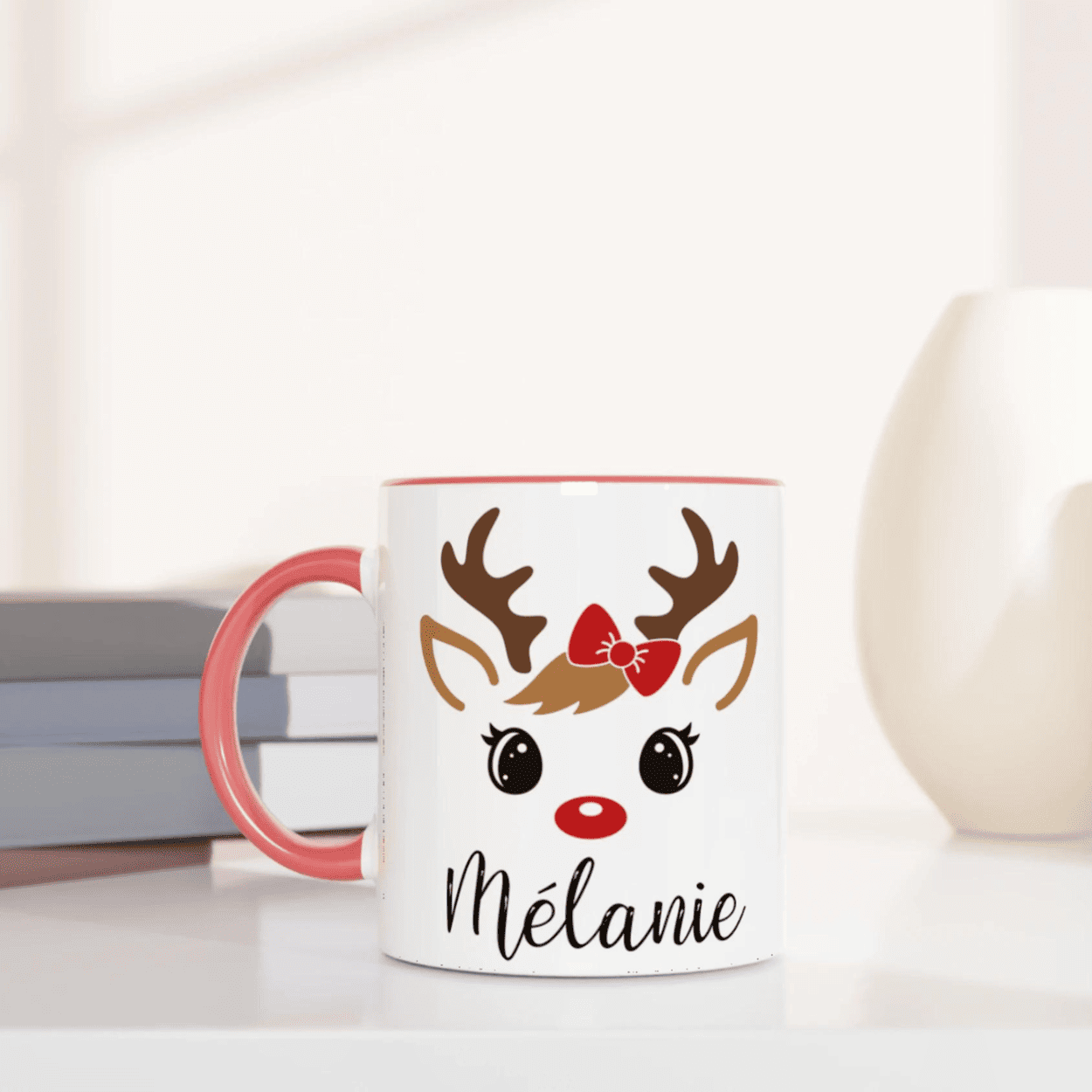Mug de Noël illustré d’un renne mignon aux yeux ouverts et nœud rouge, anse rose et intérieur rose.
