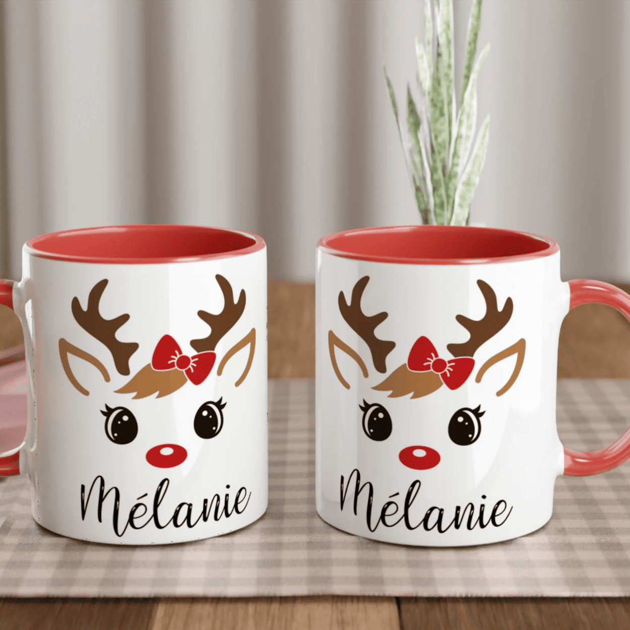 Mug de Noël décoré d’un renne festif aux yeux ouverts avec nœud rouge, anse rouge et intérieur rouge.