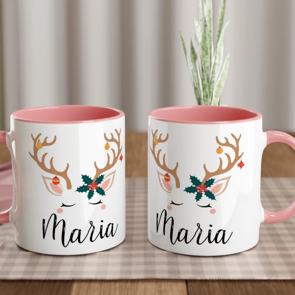 Mug de Noël décoré d’un renne aux bois ornés de décorations et feuille de houx, anse rose et intérieur rose.