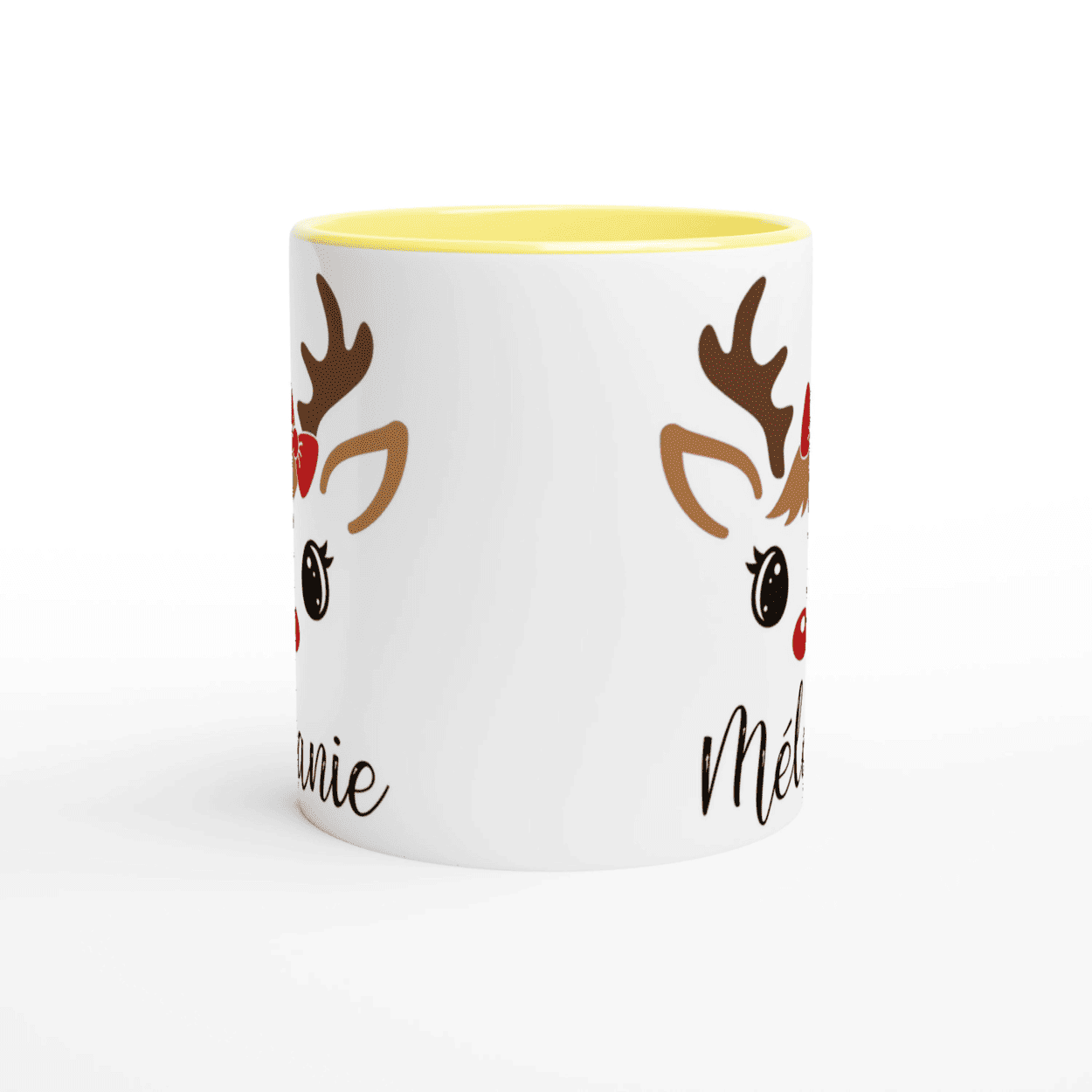 Mug de Noël avec illustration de renne aux yeux ouverts et nœud rouge, anse jaune et intérieur jaune.