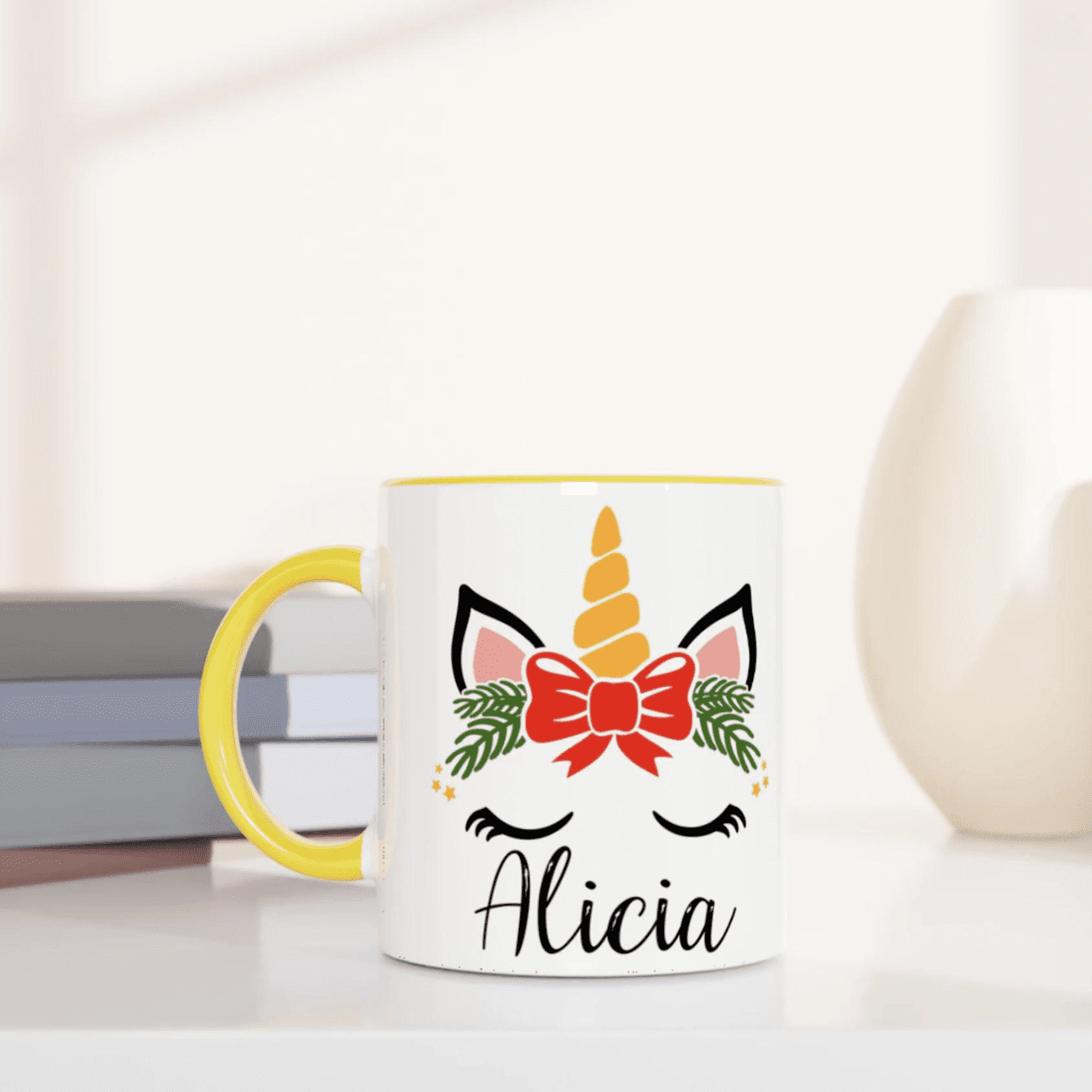 Mug blanc motif licorne de Noël avec feuillage vert et nœud rouge, anse jaune et intérieur jaune.