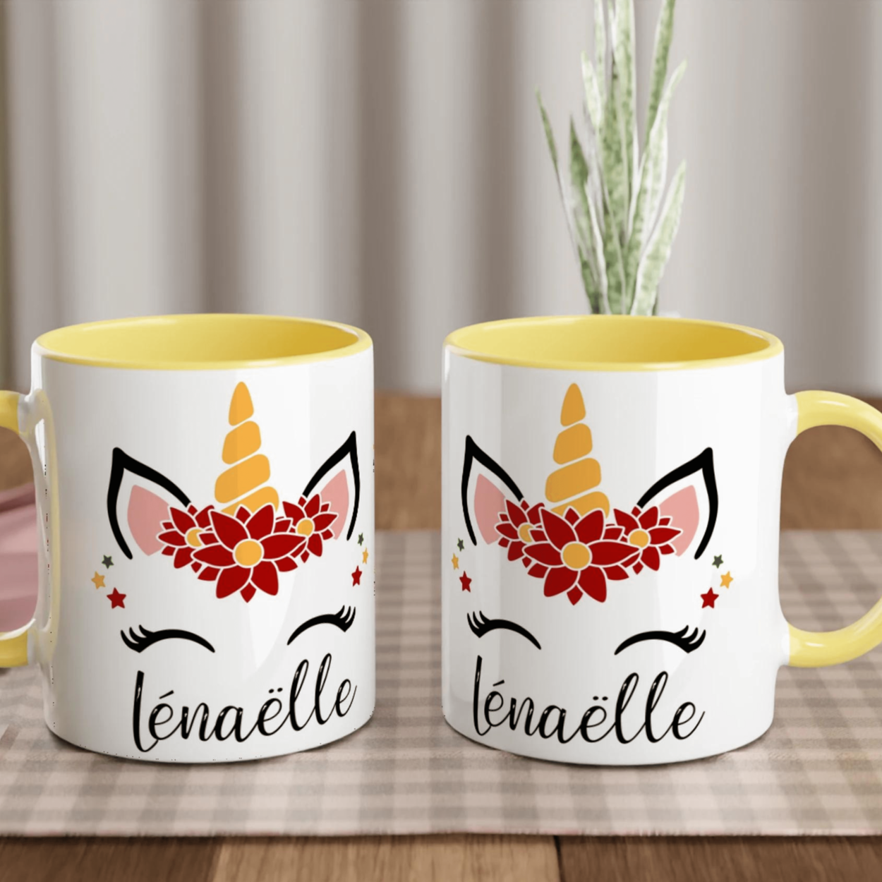 Mug blanc décor licorne de Noël avec couronne de fleurs rouges, étoiles festives et corne dorée, anse jaune et intérieur jaune.