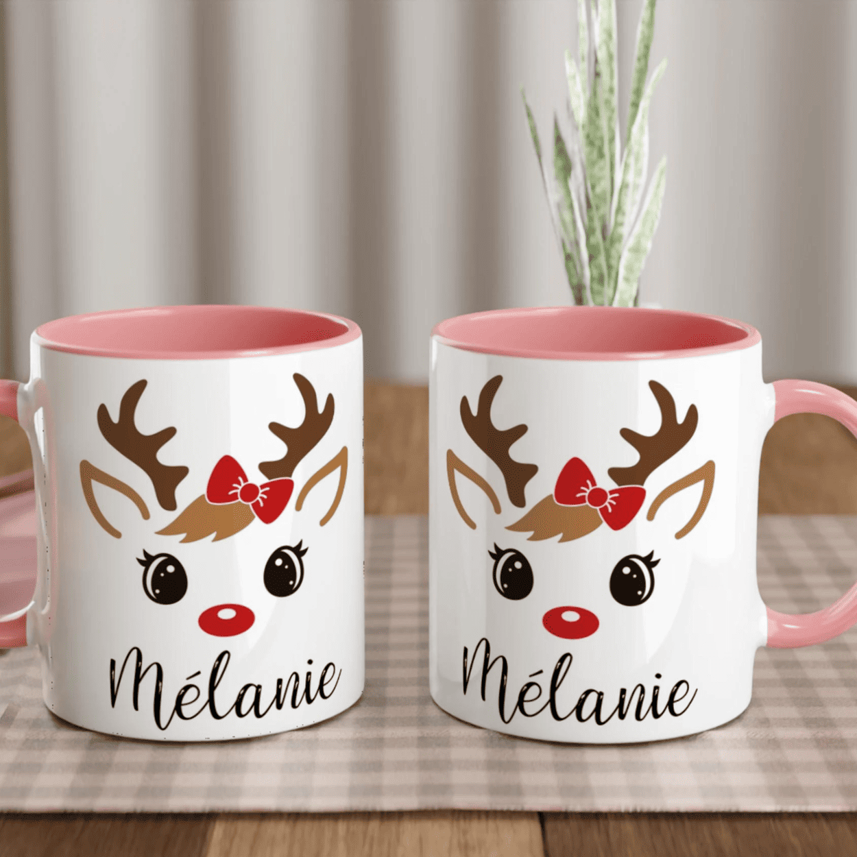 Mug de Noël illustré d’un renne mignon aux yeux ouverts et nœud rouge, anse rose et intérieur rose.