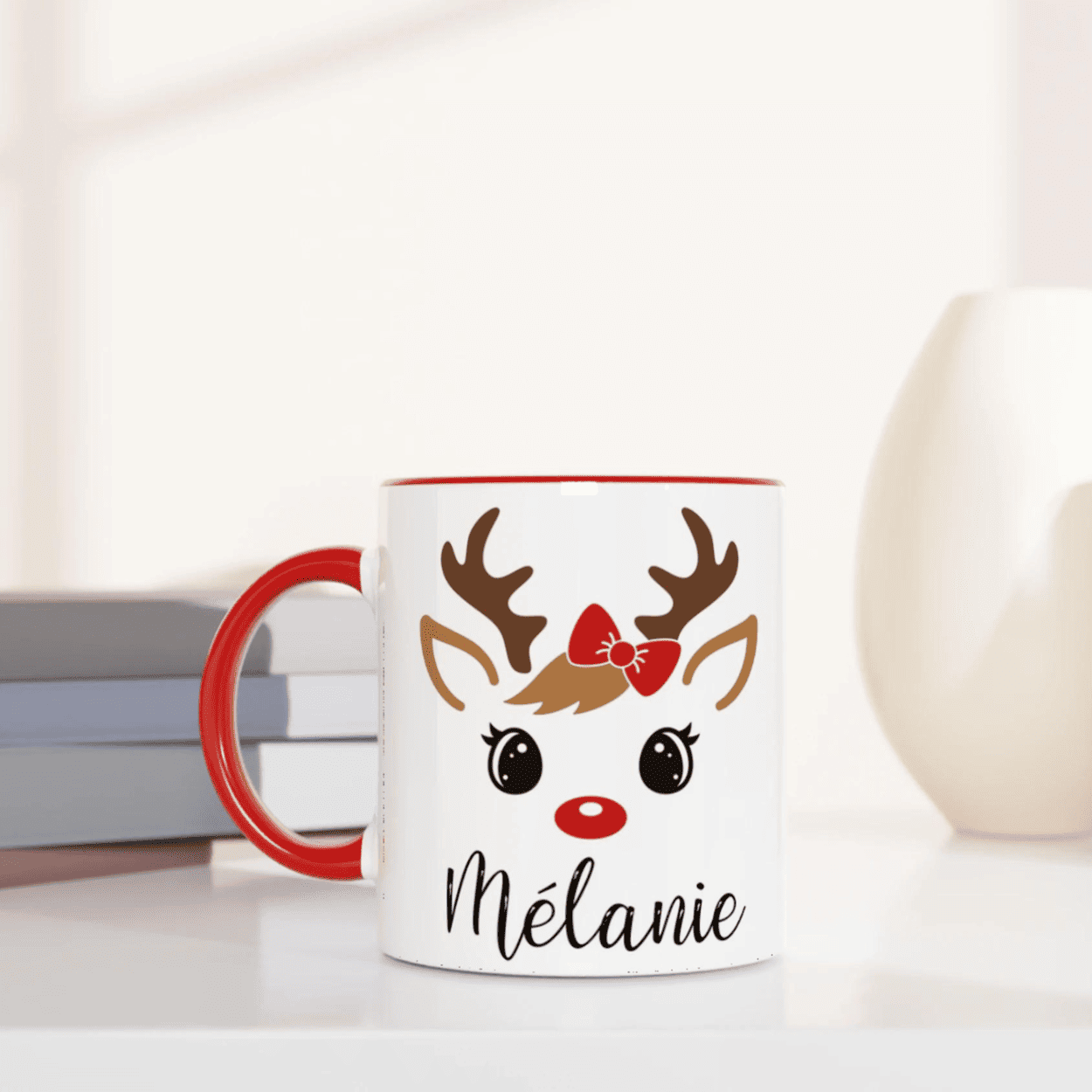 Mug de Noël décoré d’un renne festif aux yeux ouverts avec nœud rouge, anse rouge et intérieur rouge.