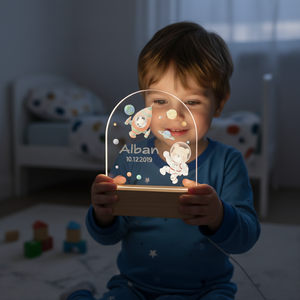 Enfant tenant une veilleuse lumineuse thème espace avec astronaute et fusée
